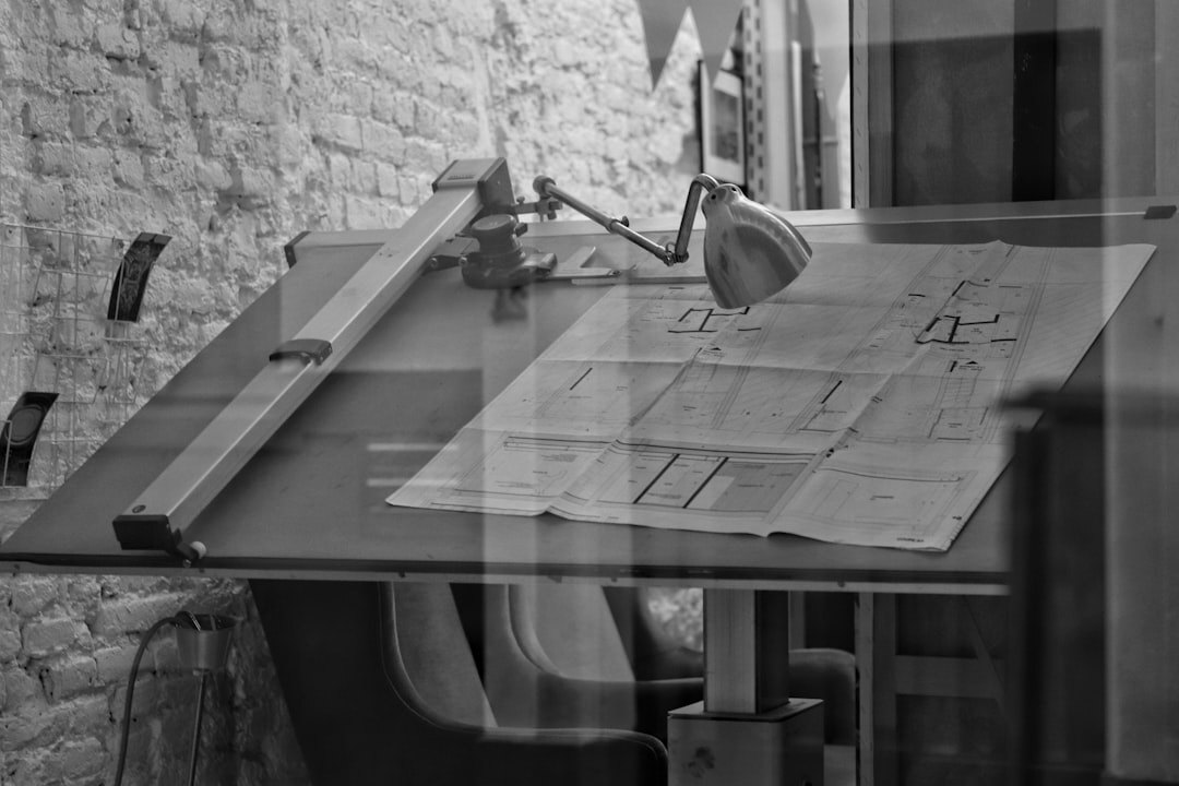 Notary signing legal documents with architectural plans on a wooden table